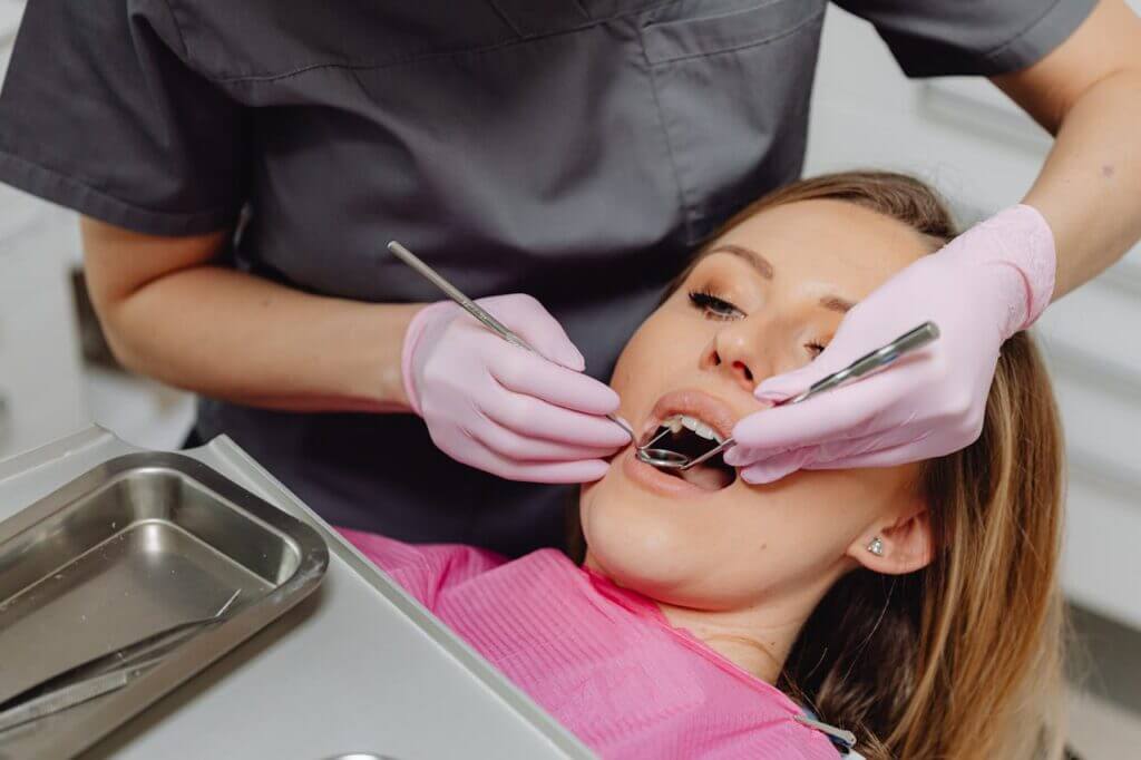 a-patient-undergoing-a-dental-procedure-6627528 Dentist performing check-up on female patient in a clinic setting, emphasizing dental care.